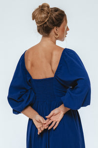 Woman wearing a blue dress with puffed sleeves on a white background