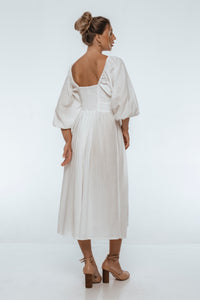 Woman wearing a white dress with puffed sleeves on a white background