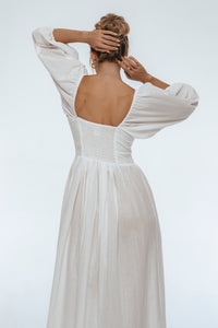 Woman wearing a white dress with a backless design on a plain background