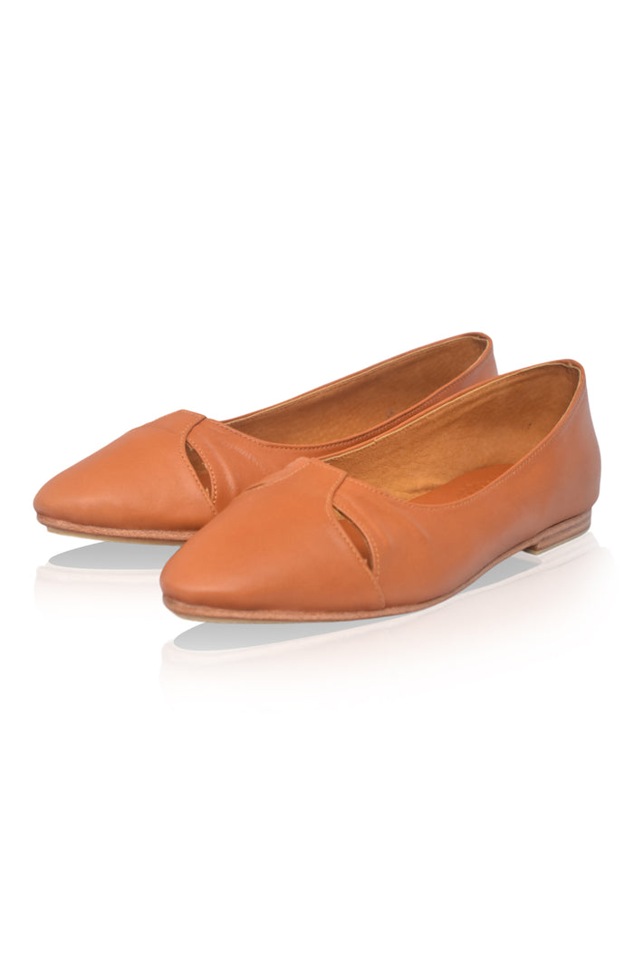Pair of tan leather flats on a white background