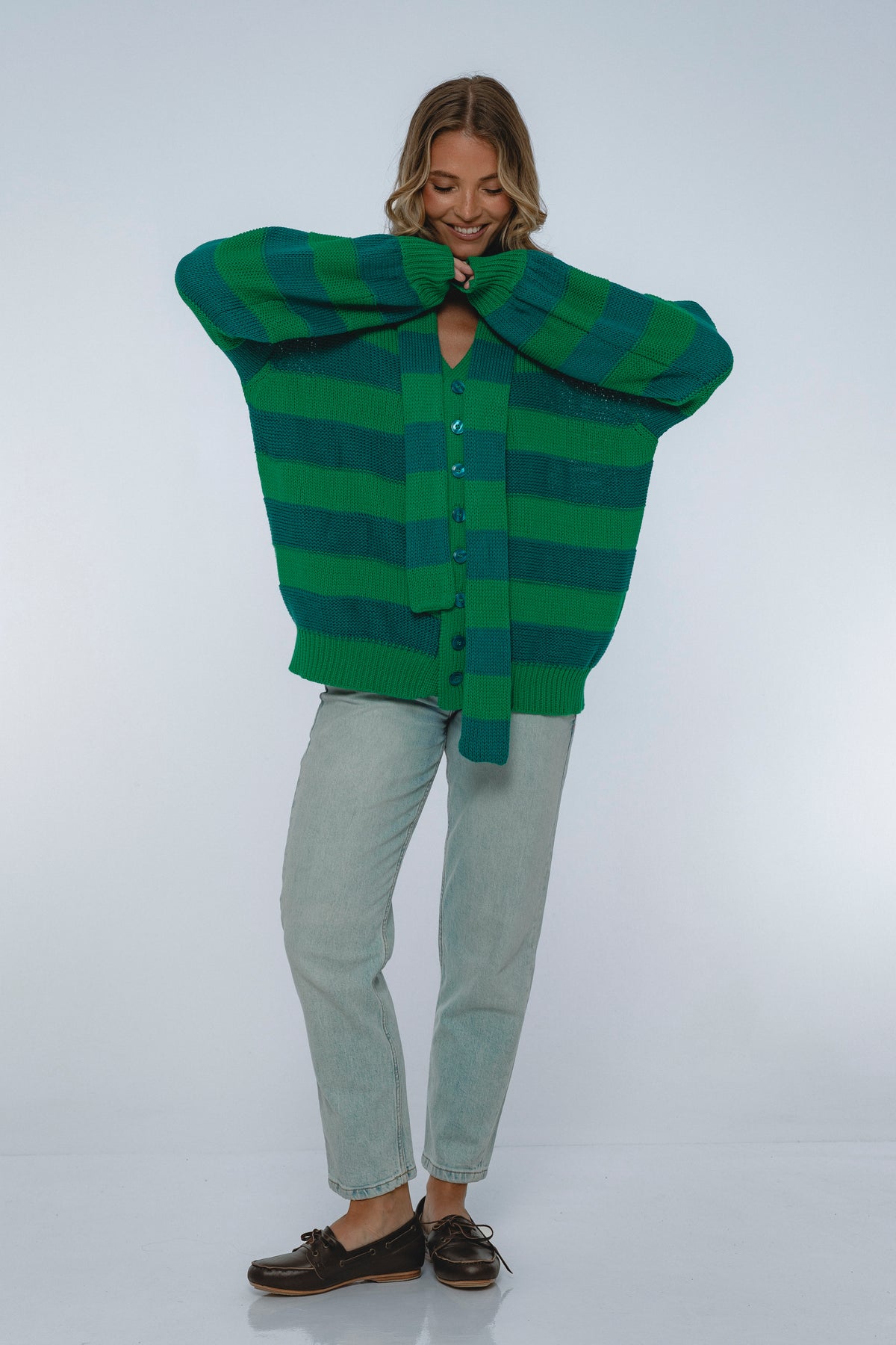 Person wearing a green and blue striped sweater on a white background