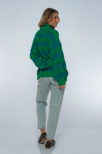 Person wearing a green and blue striped sweater on a white background