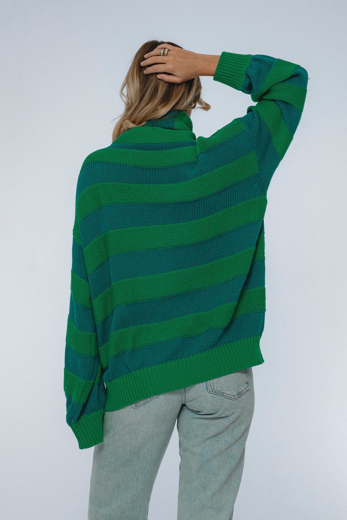 Person wearing a green striped sweater against a white background