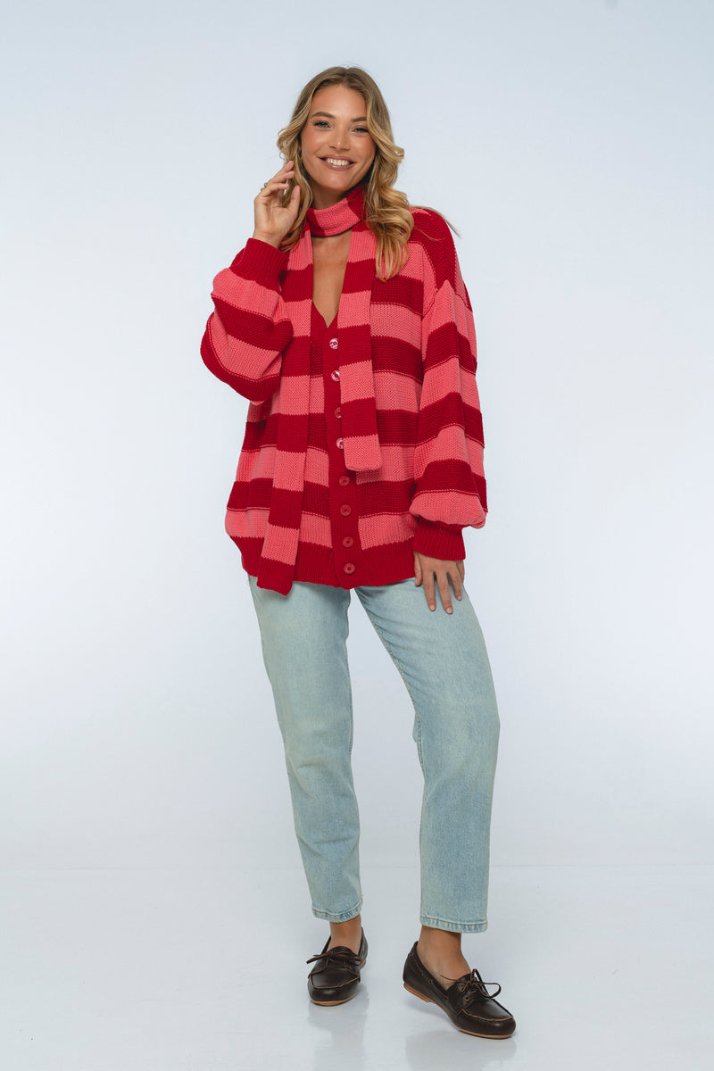 Woman wearing a red and pink striped shirt with light blue jeans on a white background