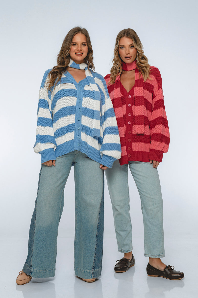 Two women wearing colorful cardigans and jeans on a white background