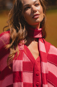 Woman wearing a red and pink checkered cardigan with a blurred background