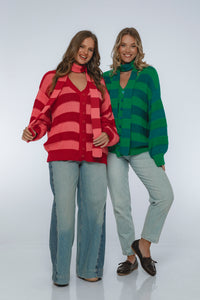 Two women wearing colorful striped sweaters on a white background