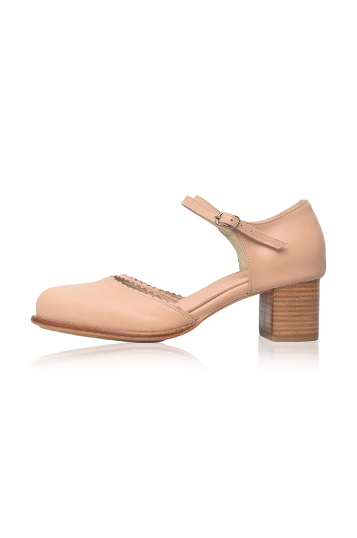 A single light beige leather Mary Jane-style block heel shoe with a decorative braided detail on the toe bed and a wooden-textured block heel, shown from a side profile on a white background.