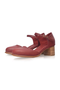 A pair of women's Mary Jane style shoes in a deep red leather, featuring a low block heel and a small gold buckle on the strap, shown against a plain white background.