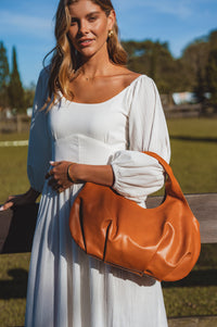 Woman holding a brown leather handbag outdoors