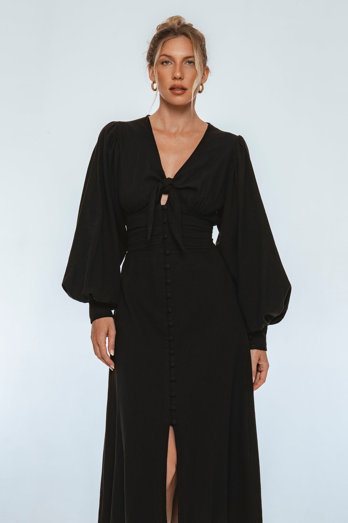 Woman wearing a black dress with long sleeves on a white background