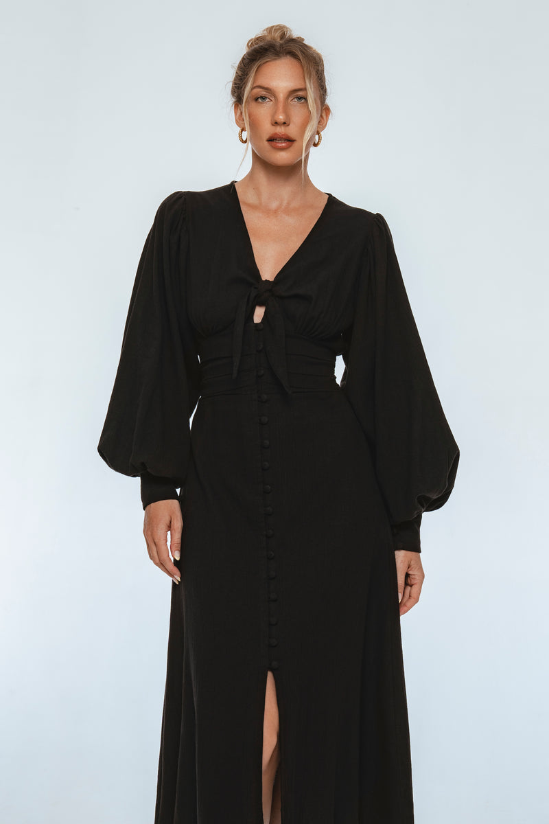 Woman wearing a black dress with long sleeves on a white background
