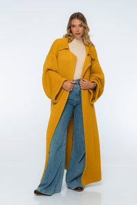 Woman wearing a mustard yellow coat and blue jeans on a white background