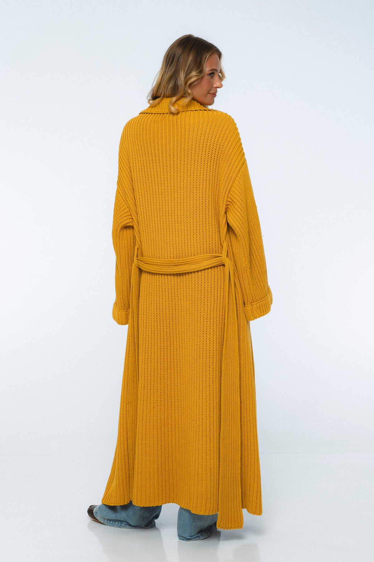 Woman wearing a mustard yellow ribbed dress on a white background