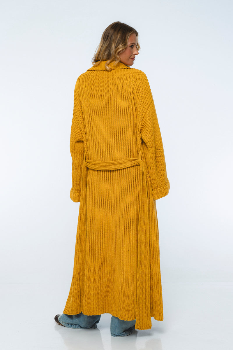 Woman wearing a mustard yellow ribbed dress on a white background