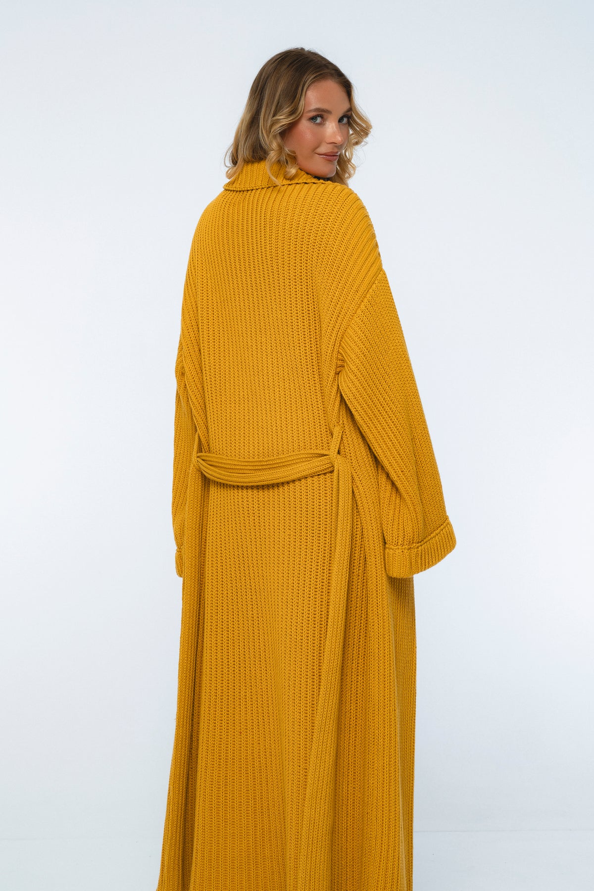 Woman wearing a mustard yellow ribbed robe on a white background