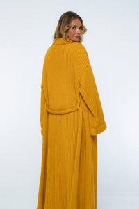 Woman wearing a mustard yellow ribbed robe on a white background