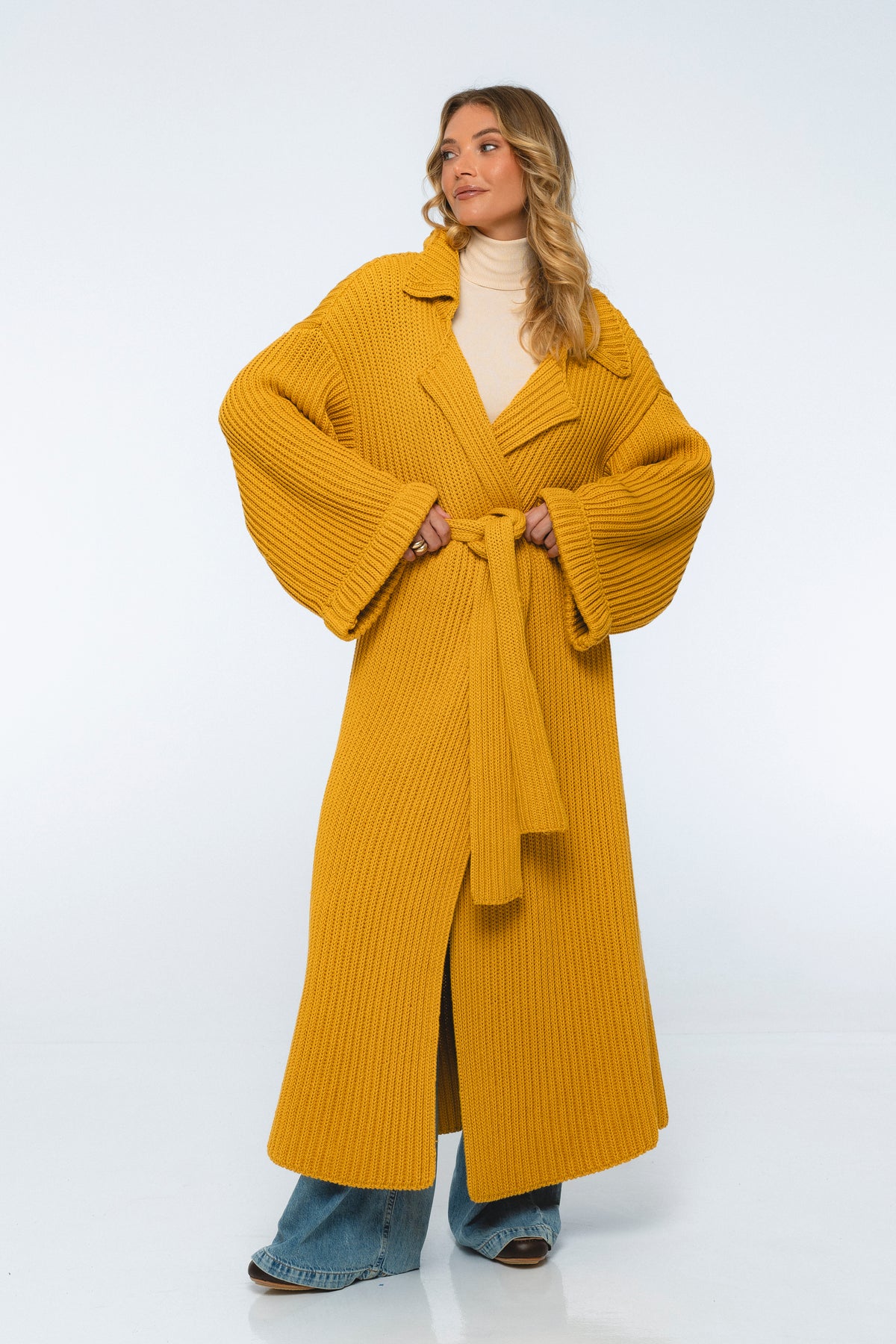Woman wearing a mustard yellow ribbed coat on a white background