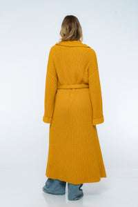 Person wearing a long yellow ribbed coat on a white background
