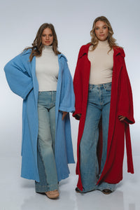 Two women wearing long cardigans and jeans on a white background