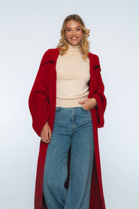 Woman wearing a red coat, beige sweater, and blue jeans on a white background