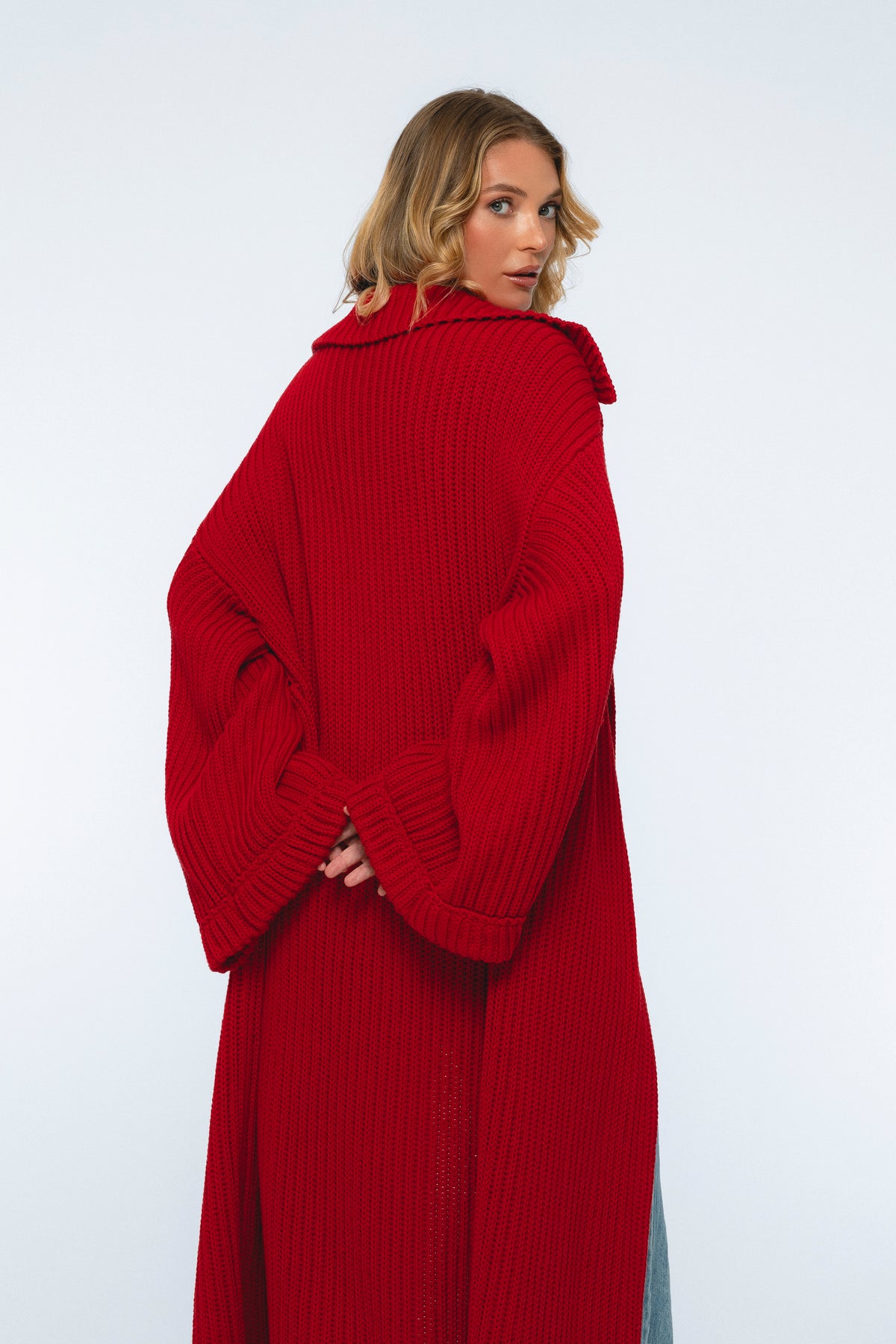 Person wearing a long red sweater against a white background
