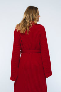 Woman wearing a red ribbed knit dress against a white background