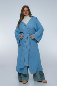 Woman wearing a blue knitted coat on a white background