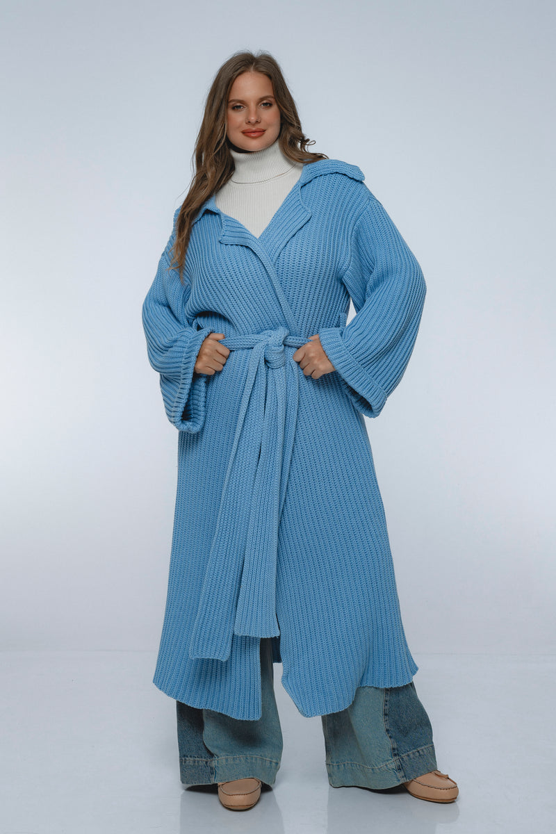 Woman wearing a blue knitted coat on a white background