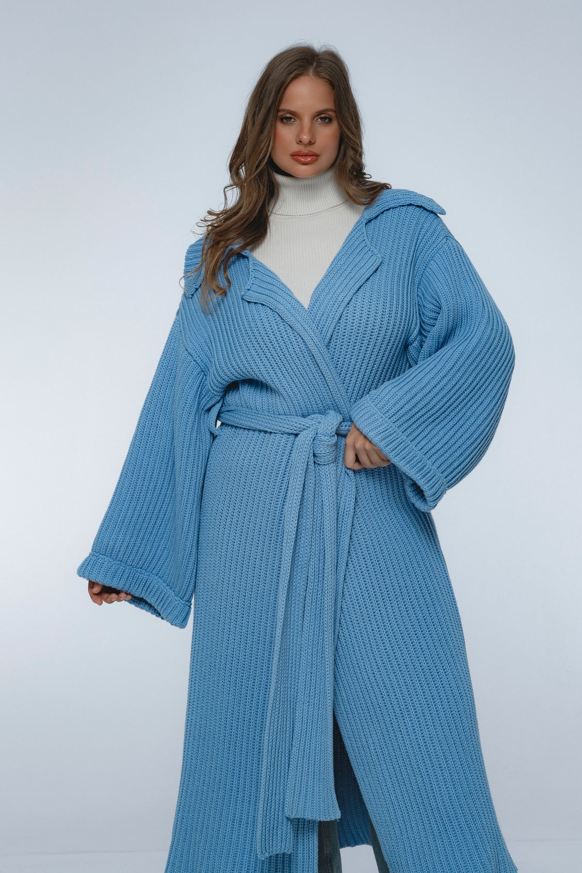 Woman wearing a blue ribbed knit robe on a white background