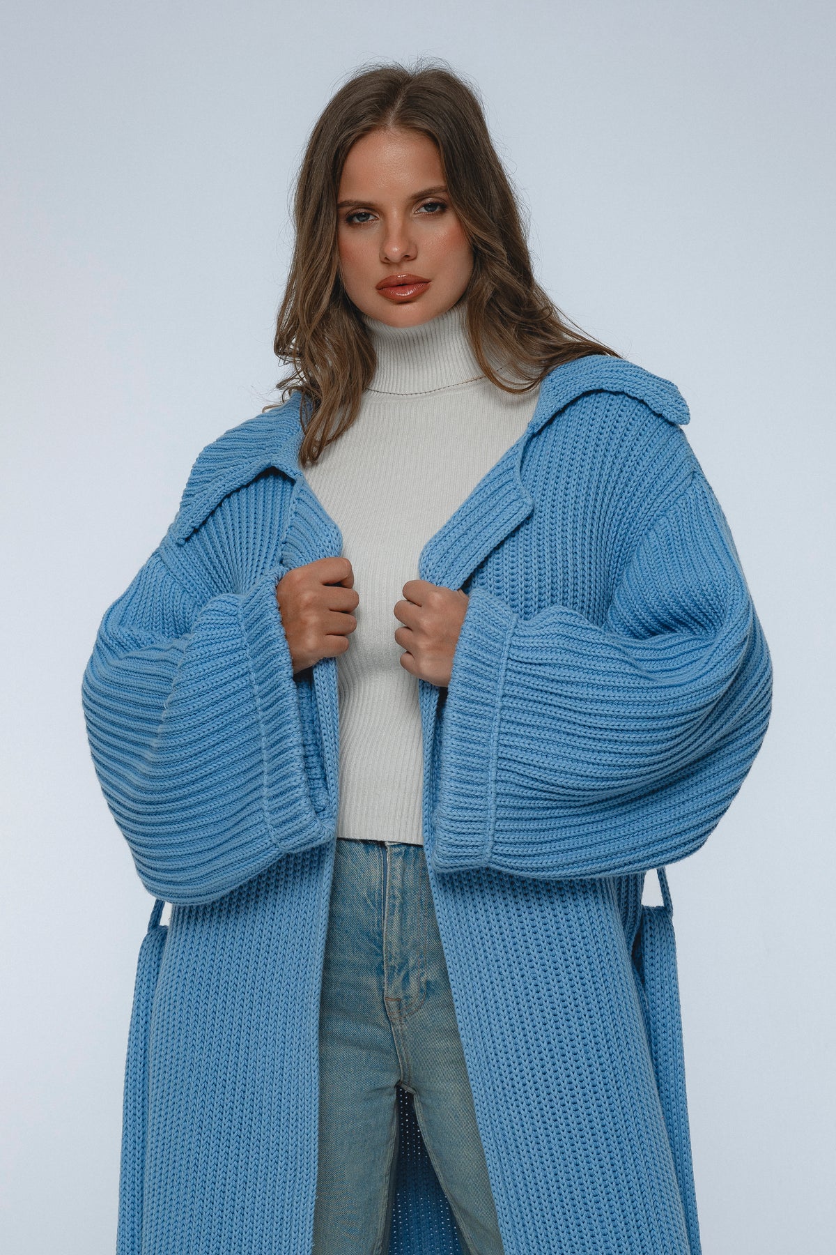 Woman wearing a blue knitted coat on a white background