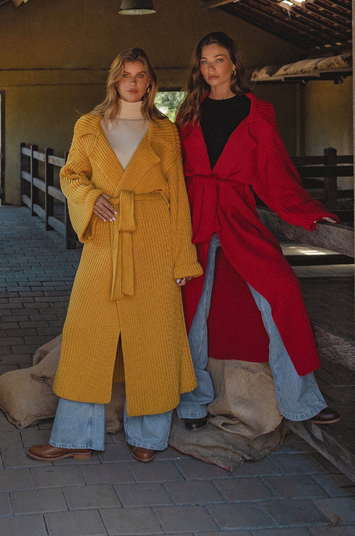 Two women wearing long coats, one yellow and one red, standing in an outdoor setting.