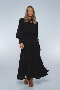Woman wearing a black dress with long sleeves on a white background