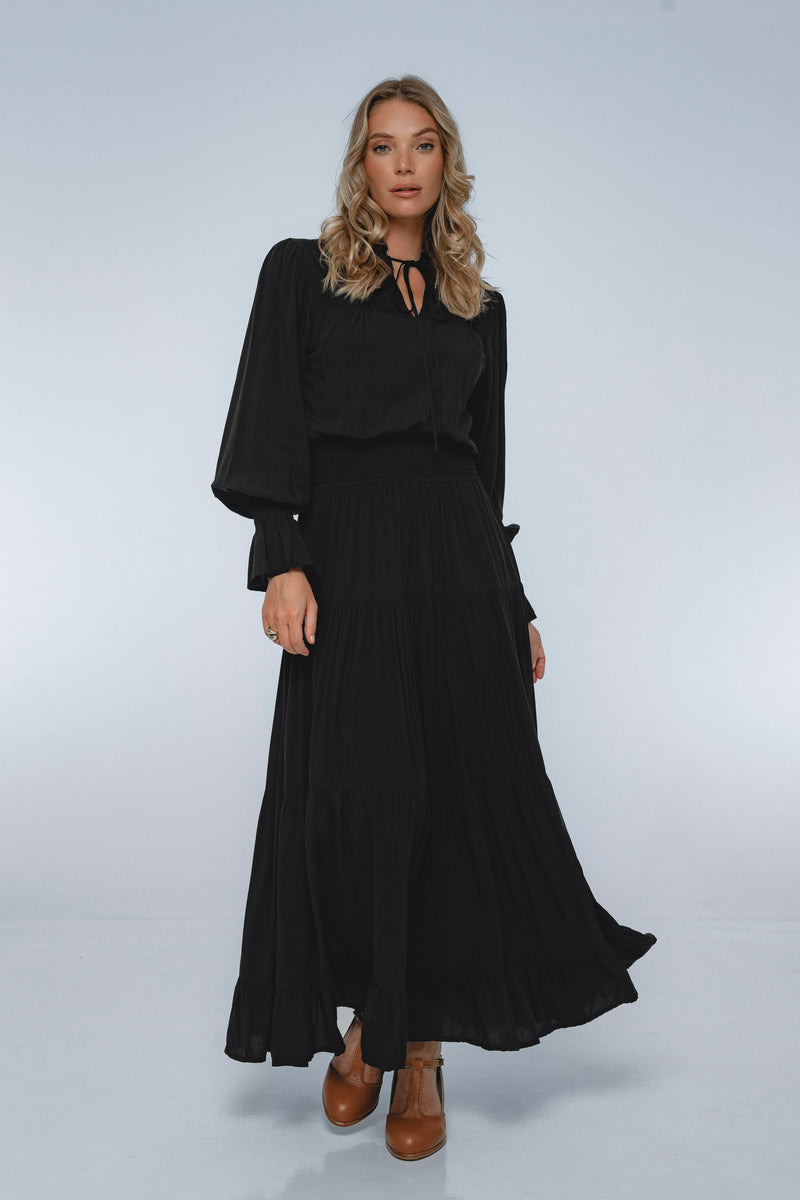 Woman wearing a black dress with long sleeves on a white background