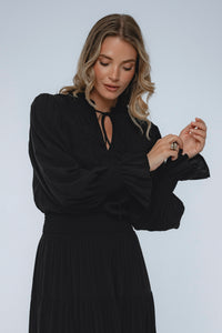 Woman wearing a black dress against a plain background