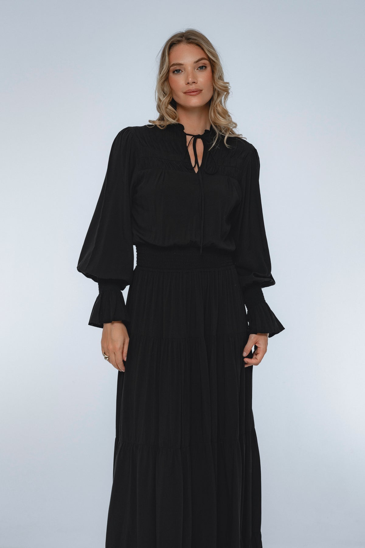 Woman wearing a black dress with long sleeves against a white background