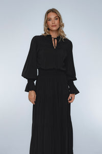 Woman wearing a black dress with long sleeves against a white background