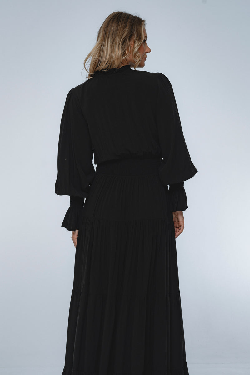 Woman wearing a long black dress against a white background