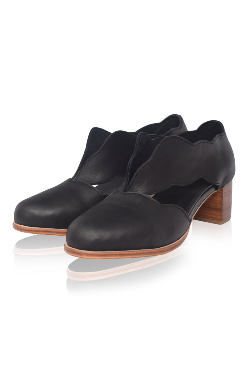 Black leather shoes with wooden heel on a white background